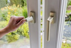 Eine Frau öffnet zum Lüften ein Fenster.